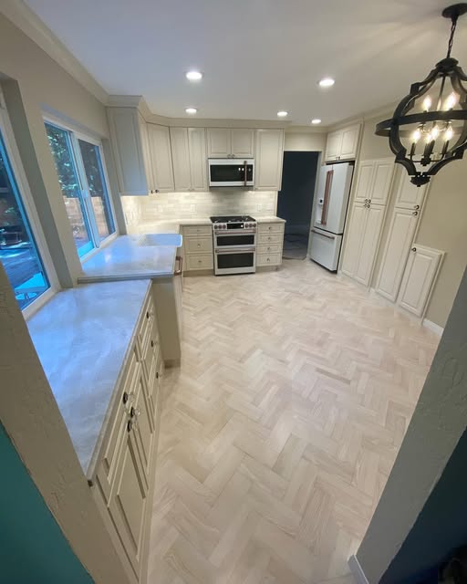 Kitchen remodel by R Twins Construction with herringbone floors and cream cabinets